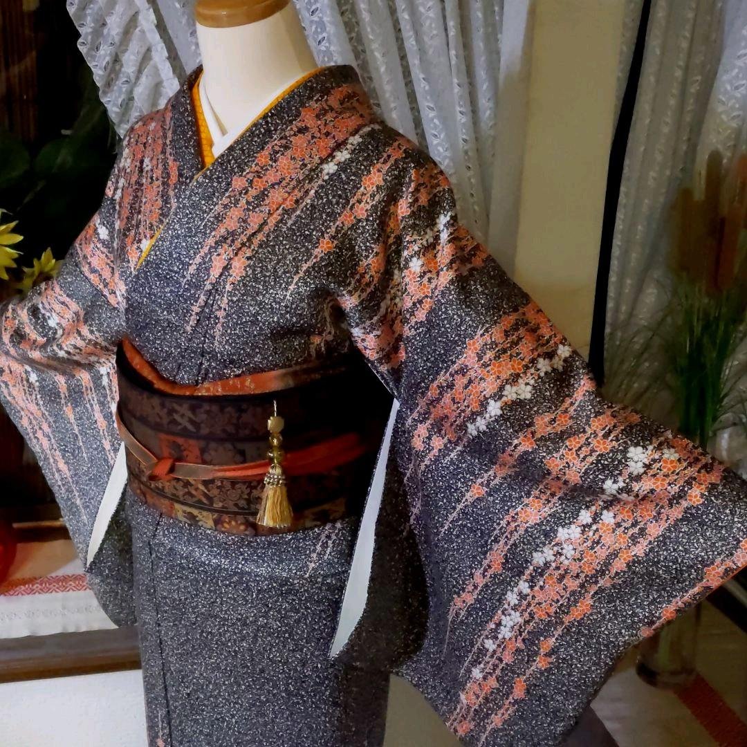 A stunning kimono made of pure silk rinzu fabric, featuring a captivating all-over dotted pattern and gracefully cascading floral motifs on a black background.